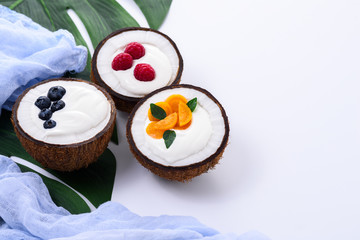 Obraz na płótnie Canvas dessert with cream and berries in coconut on white background with leaf and blue towel