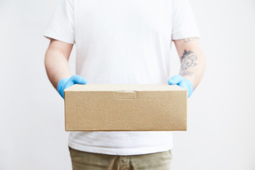 Delivery young  man in  gloves delivering parcel to a young woman during a quarantine. Concept of delivery of goods during the epidemic 