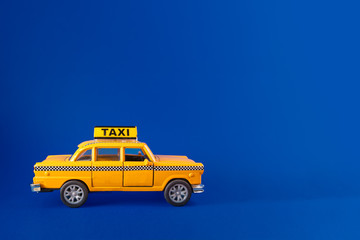 Model of yellow retro New York city taxi cab against a dark blue background. Complementary colors and copy space available