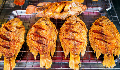 Thailand street food: grilled fish cooking in asian spicy sauce sold in the street market