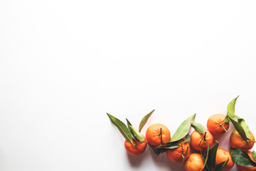 Oranges fruits composition with green leaves on white wooden background, top view