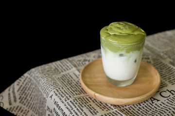 Iced Dalgona Matcha Latte, a creamy whipped matcha, on wooden tray on the table. Matcha green tea