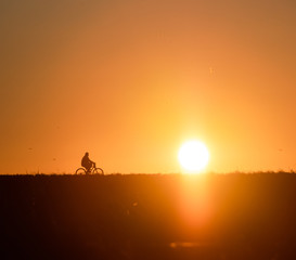 Fototapeta na wymiar Biker silhouette as the sun sets along the ridge. 