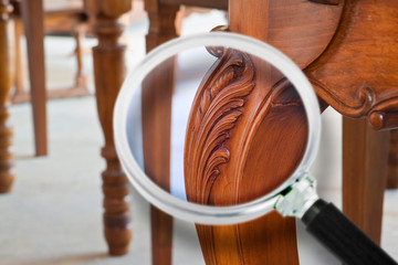 Detail of an old carved italian wooden table with floral elements just restored - concept image seen through a magnifying glass