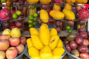 Group of sweet Tropical fruit. Fresh juicy mangos. Fruit background. Mangos, apples and limes at outdoor farmers market in Laos. Close up of variety of fruit. Big assortment of fresh fruit