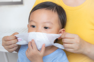 Mother putting face mask on her kid during coronavirus and flu outbreak,Asian mother avoid possible infection, COVID-19, Coronavirus, epidemic virus symptoms and Air pollution pm2.5 concept.