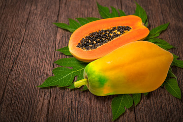 Papaya fruit, whole and half of ripe papaya fruit with seeds on wooden background