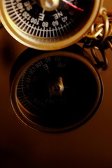 Magnetic compass encased in a brass case shot on a dark background in natural light.