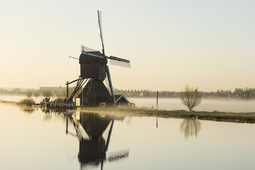 Rotating windmill rural scenery at Kinderdijk in early morning with fog on the water, the Netherlands
