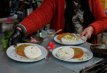 Elder women preparing and selling kanafeh in an Arab market in Akko, Israel, a traditional Middle Eastern dessert prepared with vanilla ice cream on the side