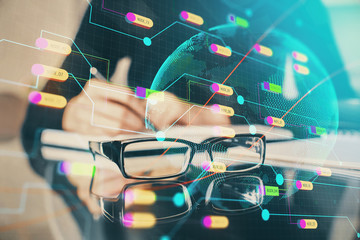 Double exposure of hands making notes with world map hologram and data theme icons. Concept of global computer data.