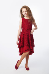 Young girl wearing red guipure dress staying on floor