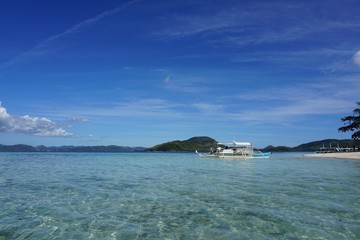 Typical filipino boat parked at the sandy beach in clear turquoise sea water - it is real paradise scenery