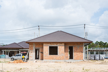 Unfinished single one storey house with brick wall progress in housing estate. House construction.