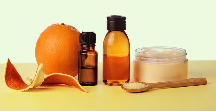 Orange essential oil in glass bottles on a yellow paper background, self-care and weight loss concept