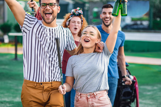 Group Of Smiling Friends Going To Play Mini Golf In The City.	