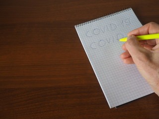 man writes to notebook COVID-19