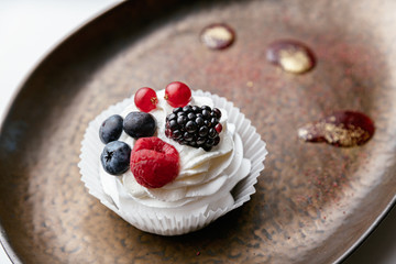 Cake with berries on a brown plate.