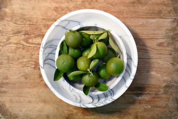fresh green citrus in the marble bow on wooden background