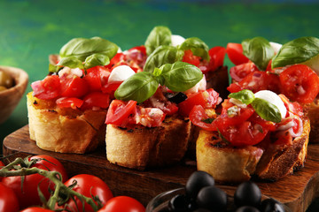 Bruschettas on cutting board on rustic background with tomatoes and basil