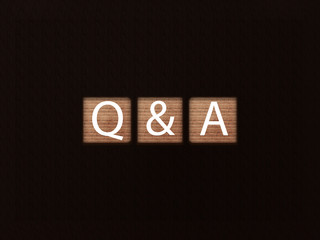 The inscription Q&A on wooden blocks on black background. Letter text on wooden cube.