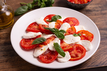 Italian Caprese dish with mozzarella cheese, fresh tomatoes, basil and extra virgin olive oil. Italian food, ideas for fast lunch, summer lunch.