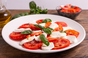 Italian Caprese dish with mozzarella cheese, fresh tomatoes, basil and extra virgin olive oil. Italian food, ideas for fast lunch, summer lunch.
