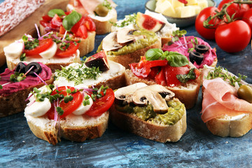 Assorted bruschetta with various toppings. Appetizing bruschetta or crudo crostini. Variety of small sandwiches. Mix bruschetta with tomatoes and basil