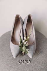 Wedding accessories. Wedding rings lie next to a flower boutonniere and women's high heel shoes
