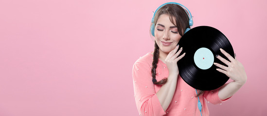 Woman smiling while holding vinyl record and wearing headphones