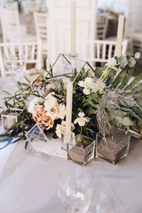 Stylish wedding floristics. Banquet tables decorated with arrangements of flowers, herbs and candles