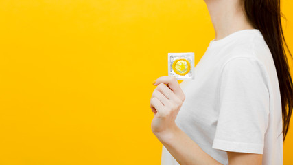 Side view woman holding a condom with copy space - obrazy, fototapety, plakaty