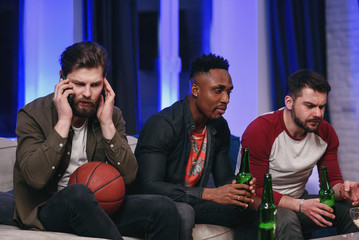 Fierce noisy likable 30s multiracial male friends encouraging with shouts their favourite football...