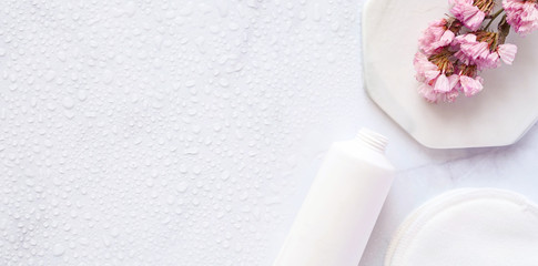Сare product cream, pads, flower. bath accessories on white marble water drops background, top view, copyspace, banner. Bodycare and beauty treatments concept, organic bath products, daily routine