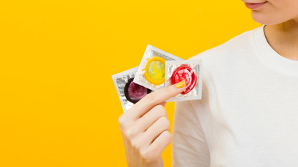 Person holding three different condoms with copy space