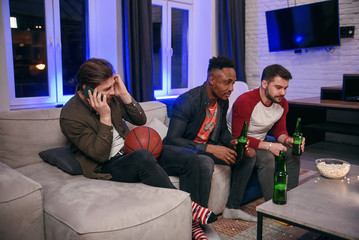 Fierce noisy likable 30s multiracial male friends encouraging with shouts their favourite football...