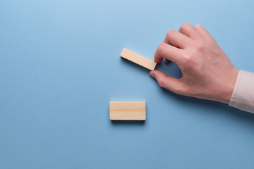 The concept of cost optimization in business. Hand holds wooden blocks on a blue background.