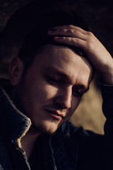 A brutal portrait of a young sad man in a denim jacket