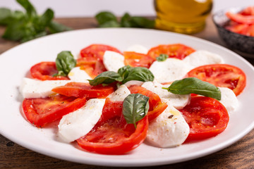 Italian Caprese dish with mozzarella cheese, fresh tomatoes, basil and extra virgin olive oil. Italian food, ideas for fast lunch, summer lunch.