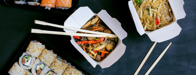 Asian food delivery. Home delivery. Boxes with noodles and rolls close up. Banner.