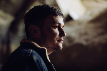 Portrait of a young serious man in the mountains in a cave
