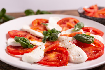 Italian Caprese dish with mozzarella cheese, fresh tomatoes, basil and extra virgin olive oil. Italian food, ideas for fast lunch, summer lunch.