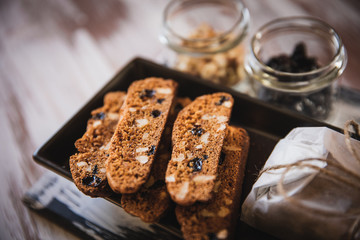 Italian biscotti cookies with walnuts and raisins, shot on a dark wooden background. Background for cooking and home baking.