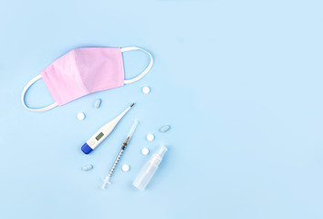 Mask, thermometer, syringe and sanitizer are on blue background.