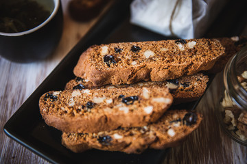 Italian biscotti cookies with walnuts and raisins, shot on a dark wooden background. Background for cooking and home baking.