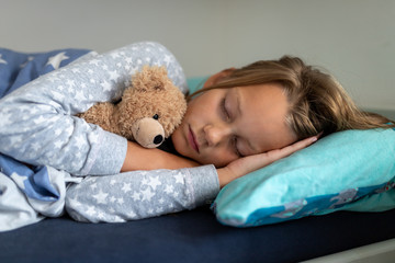 Girl is sleeping and cuddles with her teddy bear