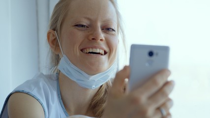 A young woman in a mask during the quarantine period communicates in the video chat.