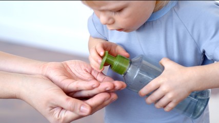 Mom and son washing hands with a disinfectant to prevent infection.