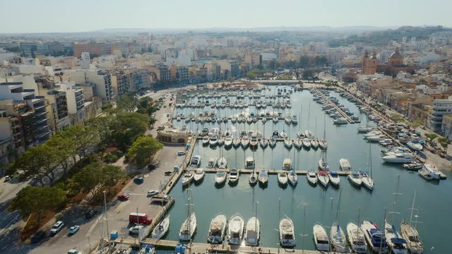 Aerial view of Msida marina, church, yachts, boats. Sunny day. Camera moves forward. Malta island