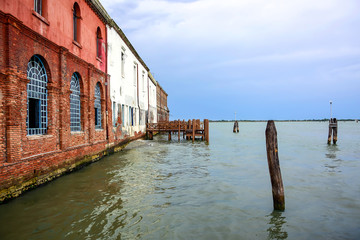 Burano / Venice, Italy - Walls of burgundy and white houses on the island of Burano, coast of the Venetian lagoon, Adriatic Sea, in the summer during the daytime.